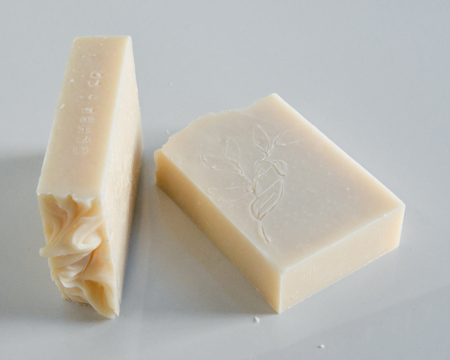 Two creamy white bars of soap laying on a white background