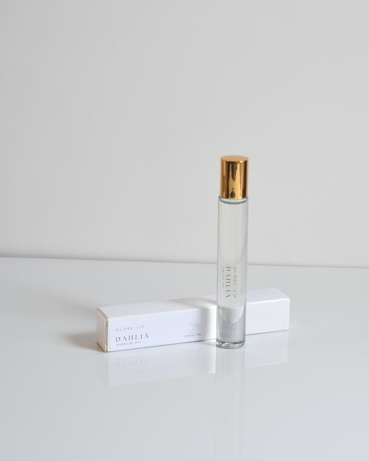 A clear glass bottle of Dahlia perfume oil with a gold-colored cap, labeled with the brand Ochre & Co.