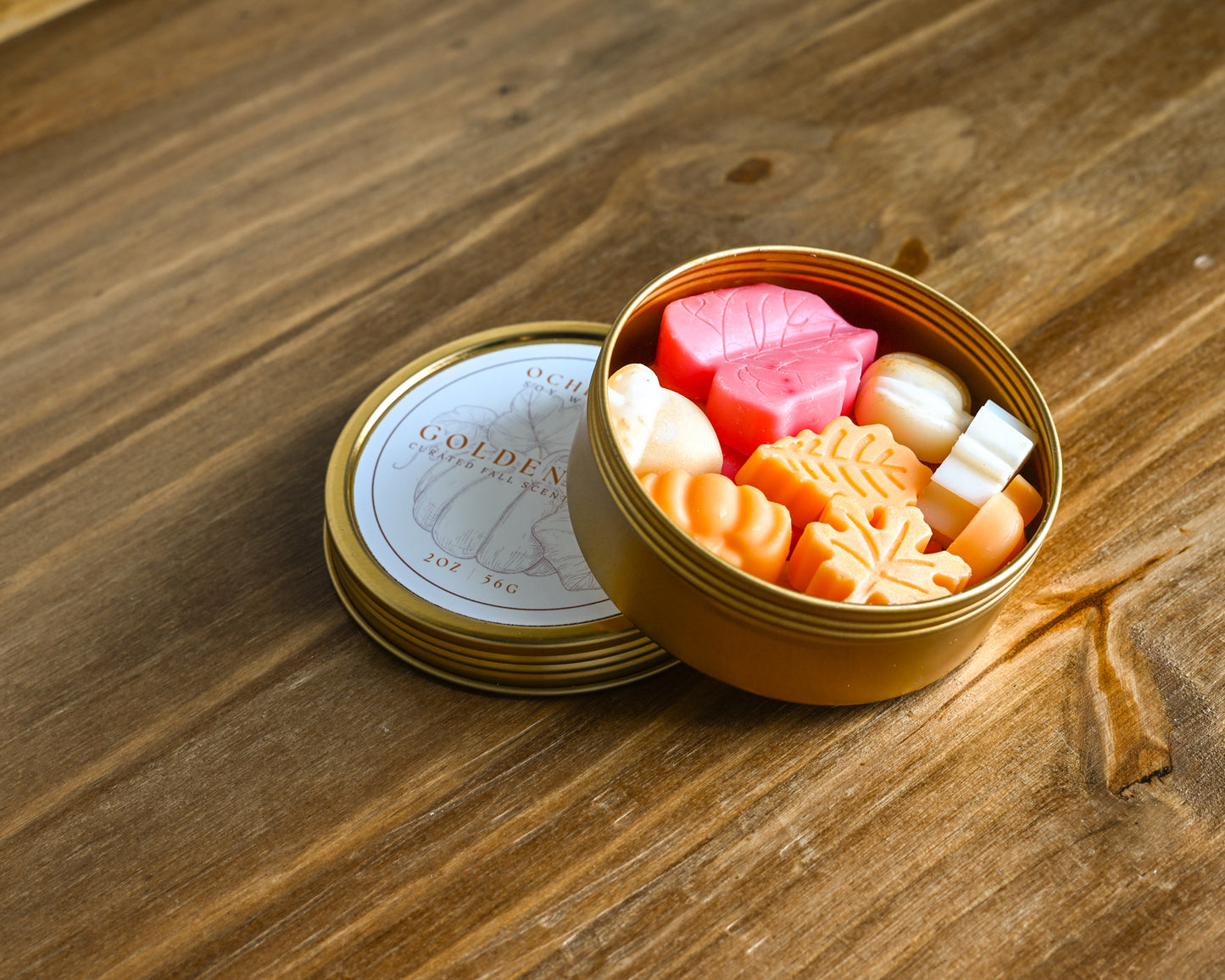 Golden Hour gold tin of varietal fall wax melt scents on a wood background