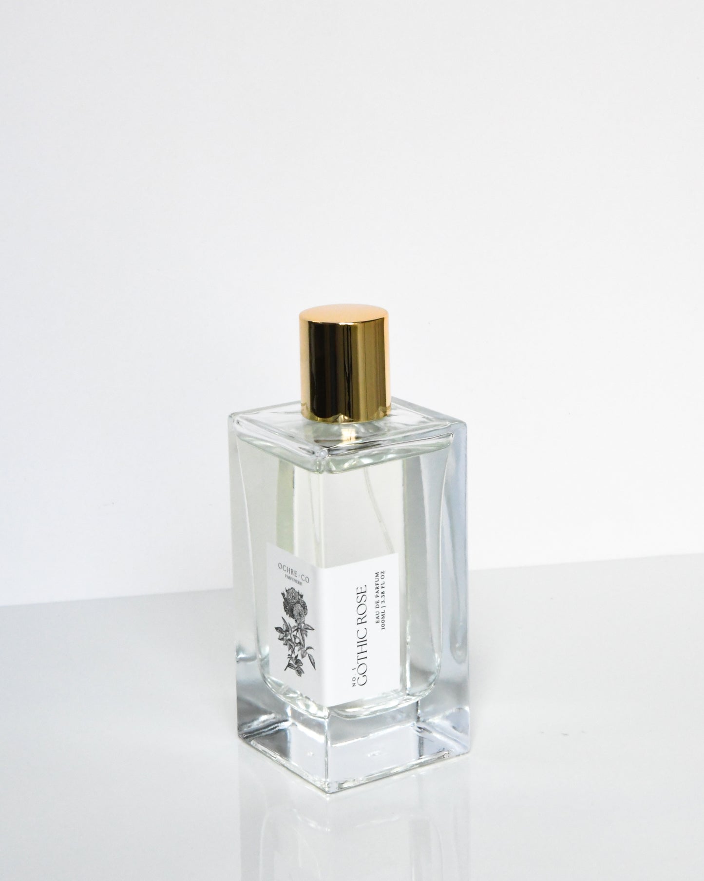 A clear glass bottle of Gothic Rose eau de parfum with a gold-colored cap.