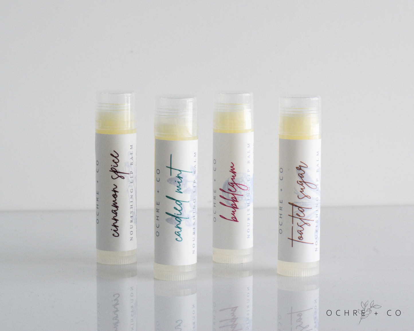 A group of four lip balms standing up on a white background