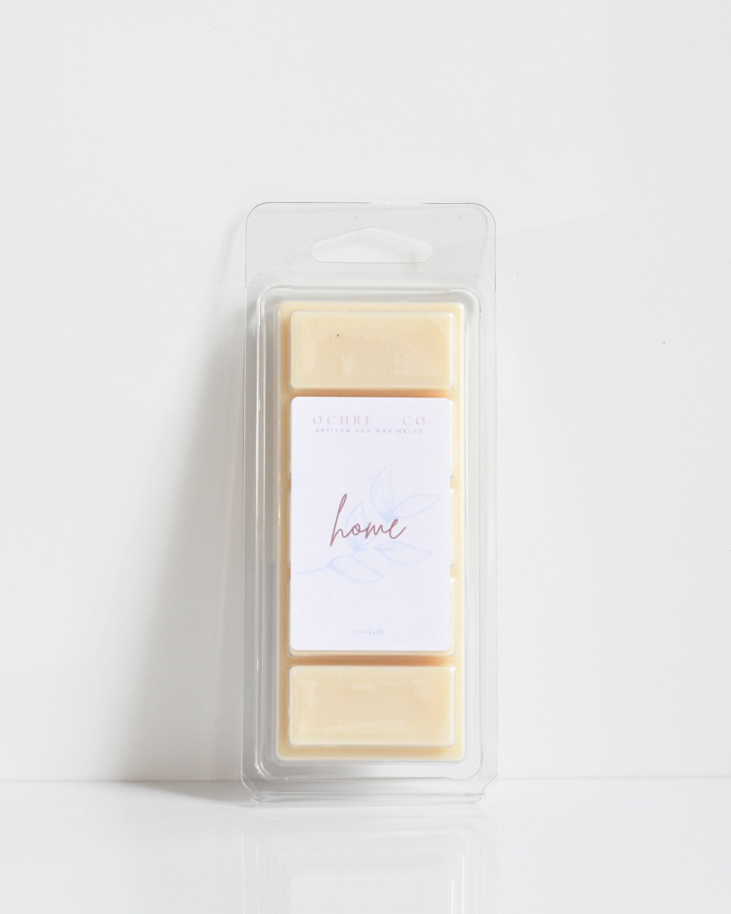A clear plastic package containing beige wax tarts with a white label on top that says 'home'.