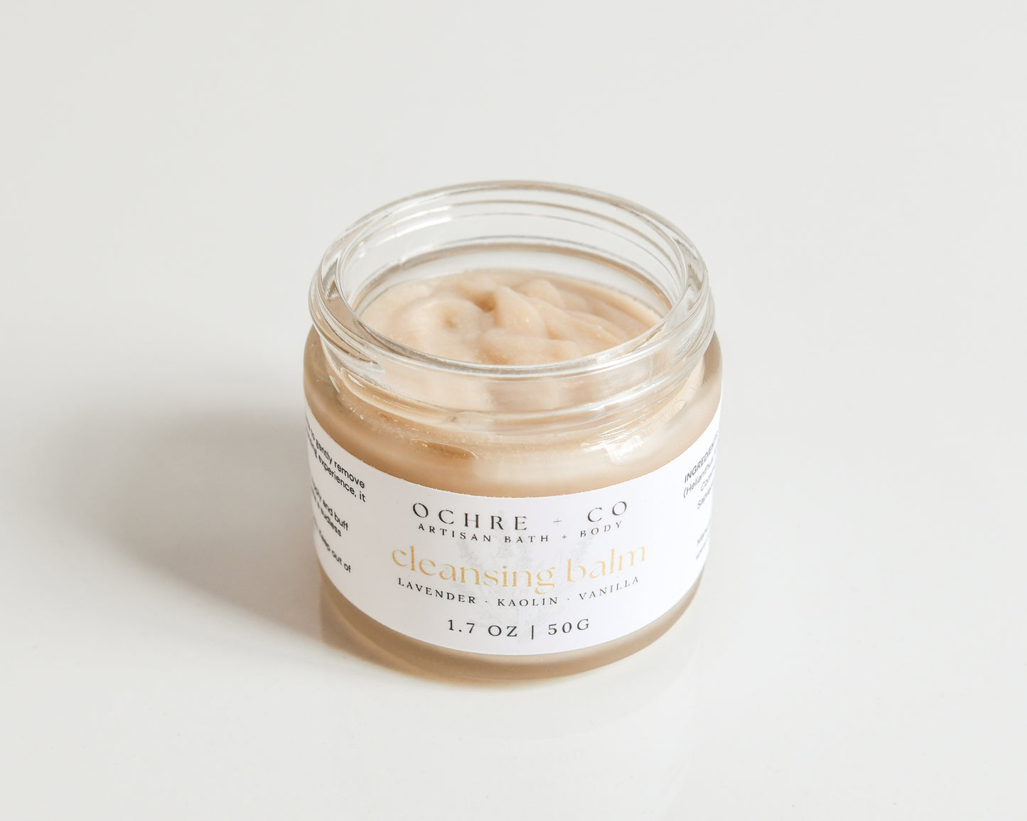 Small glass jar without a lid to expose the creamy texture with a label on a white background