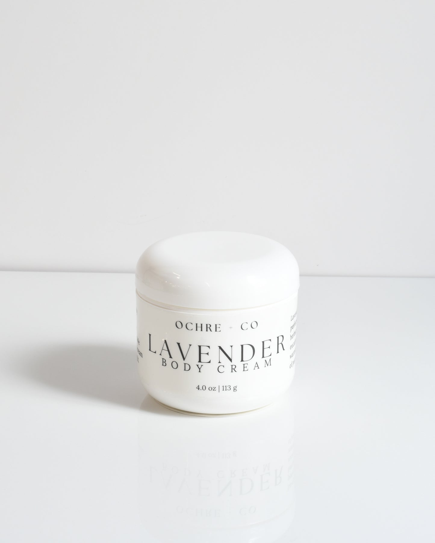 A white jar labeled 'LAVENDER BODY CREAM' by OCHRE CO. placed on a white surface.