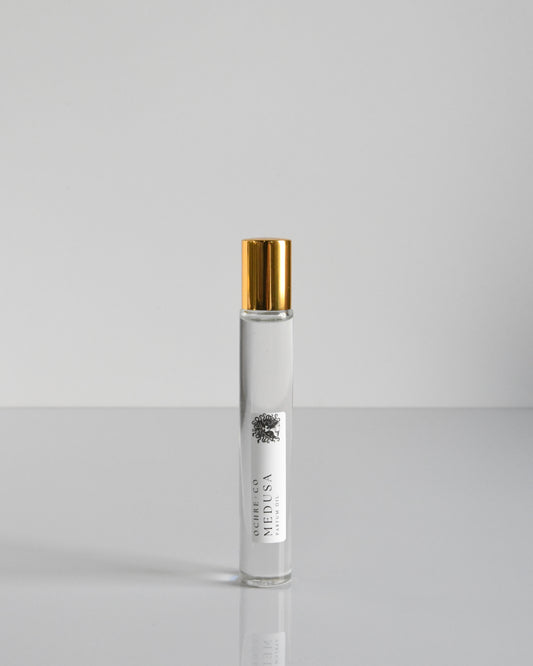 A clear glass bottle of Medusa perfume oil with a gold-colored cap, displayed against a white background.