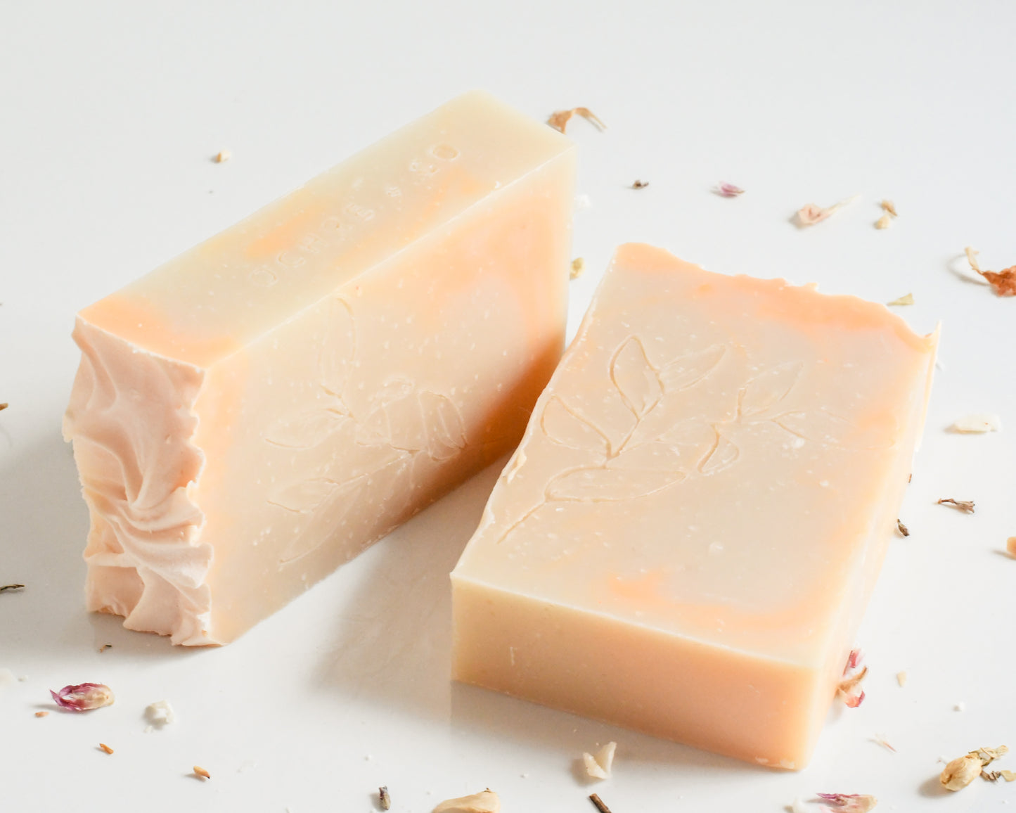 Two orangish soap bars on a white background with scattered dried florals