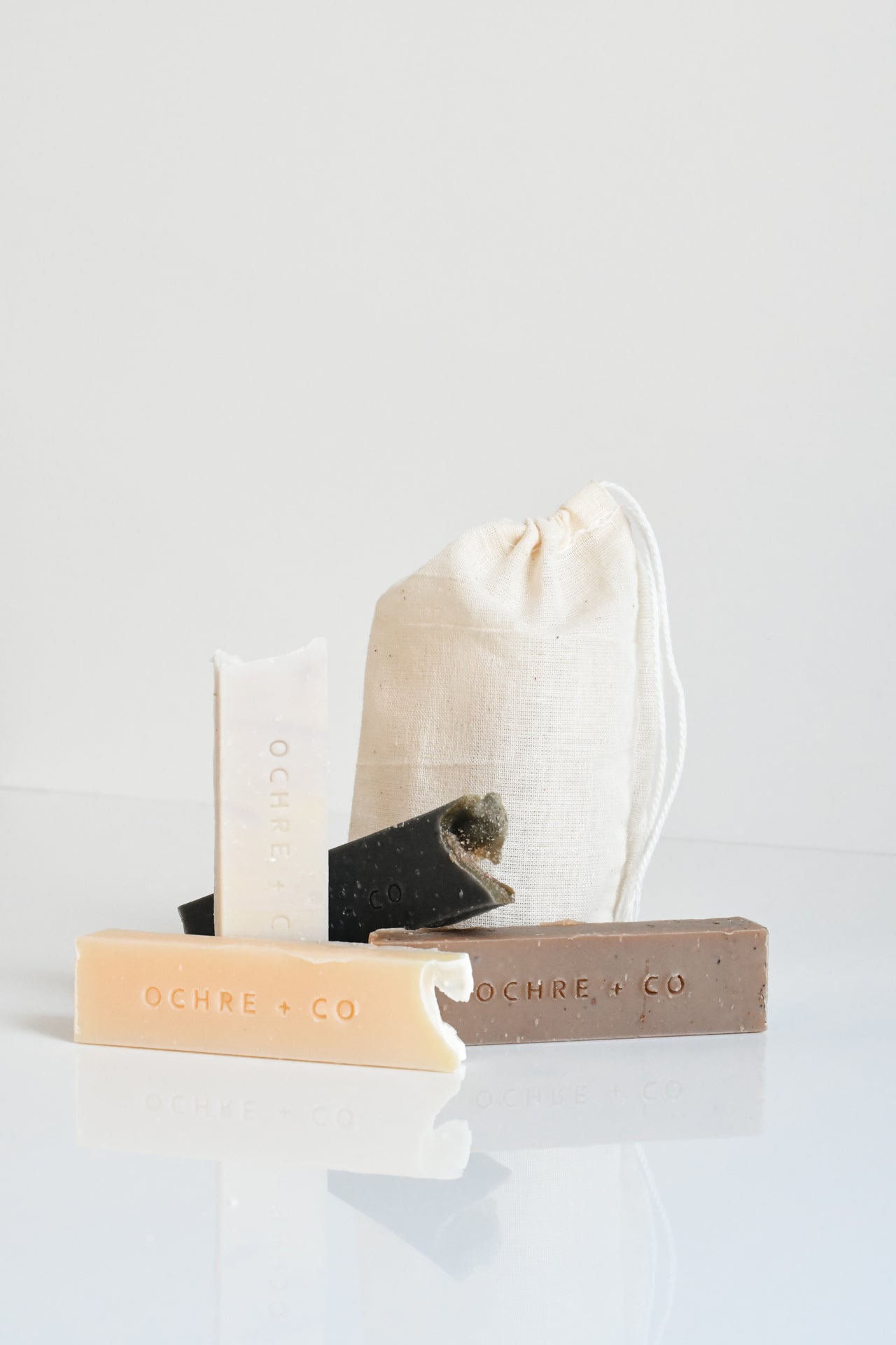 Four sample slices of soap bars with a muslin bag on a white background