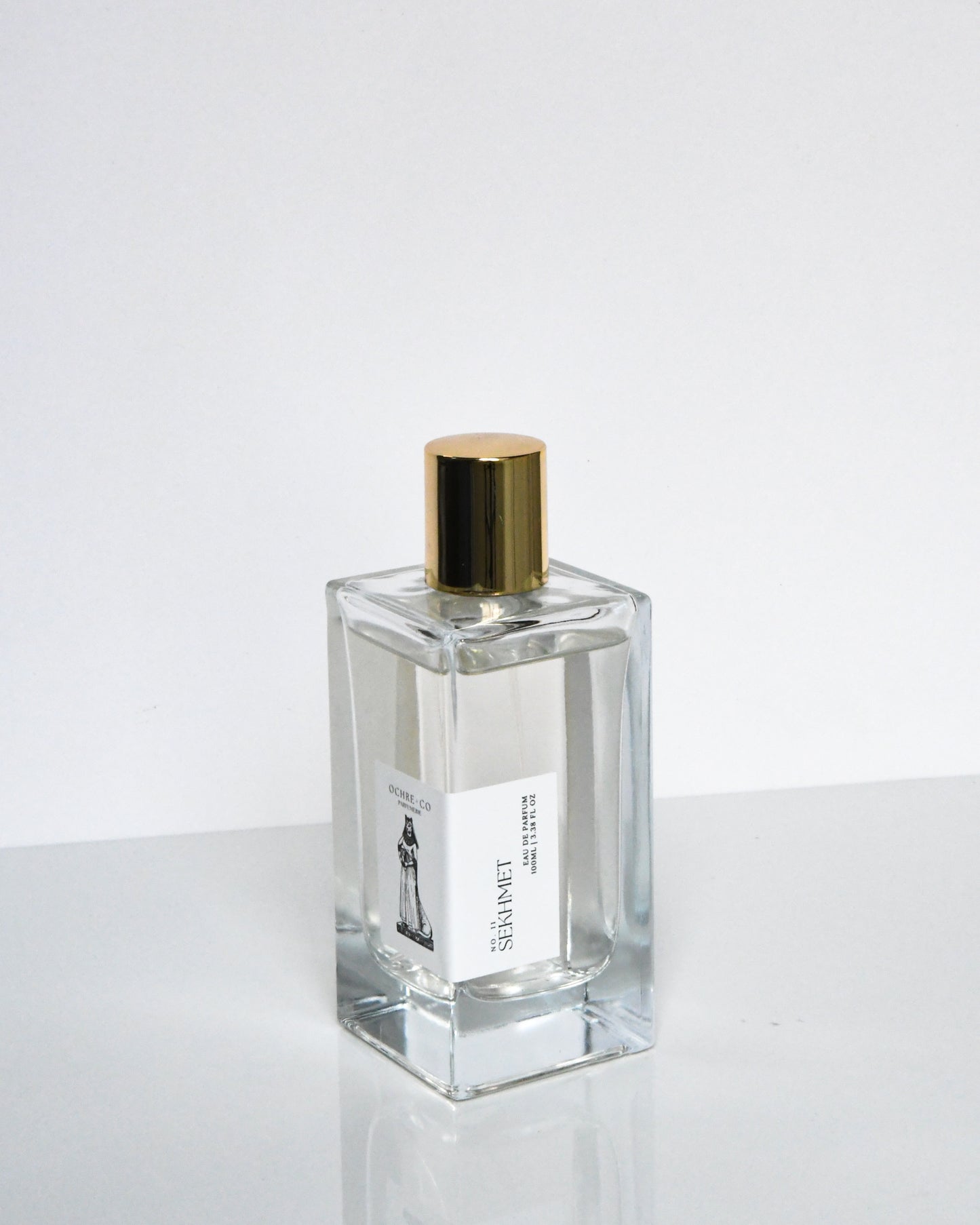 A clear glass bottle of Sekhmet Eau de Parfum with a gold-colored cap, displayed against a white background.