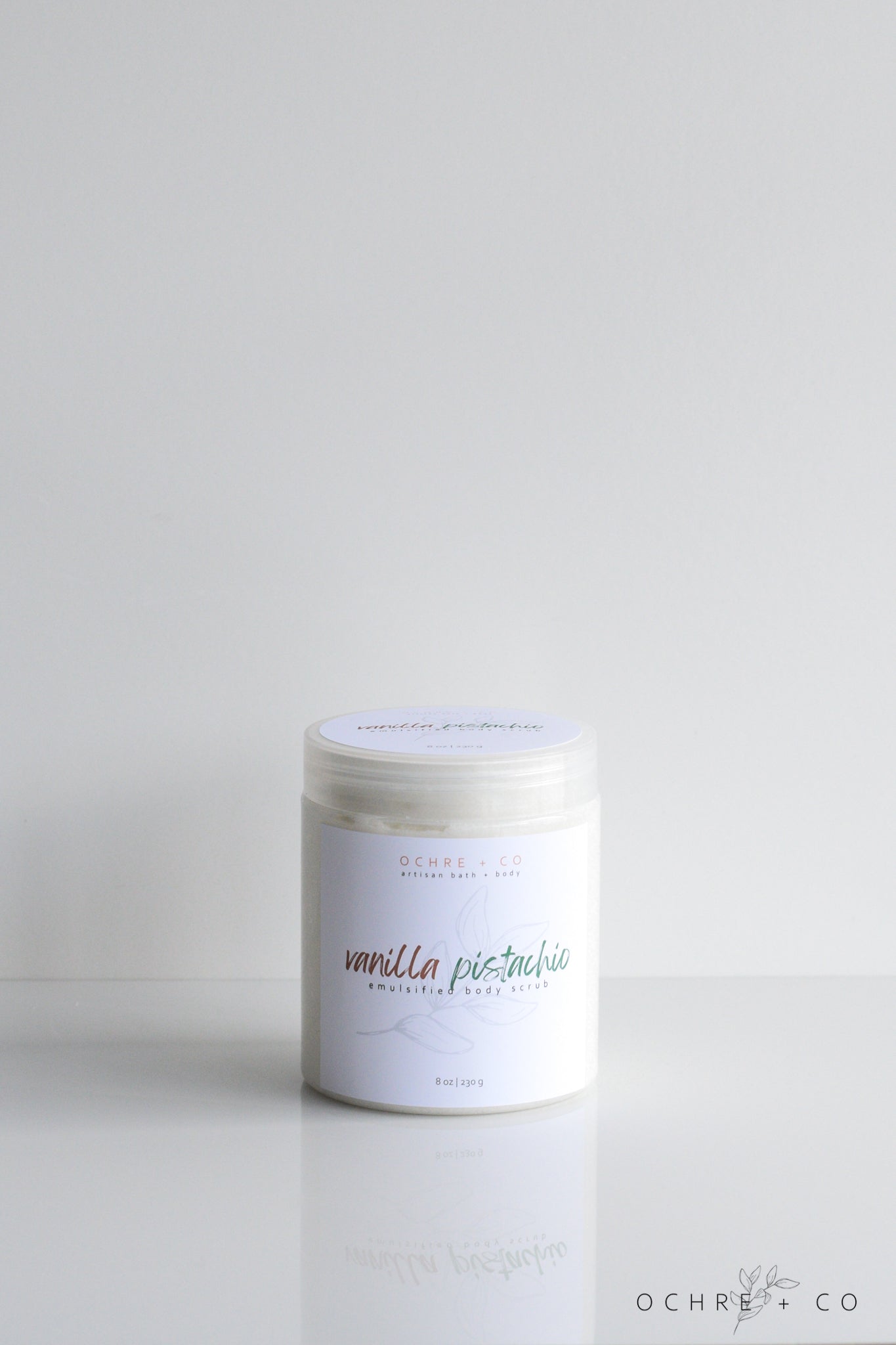 A jar of vanilla pistachio sugar scrub on a white background