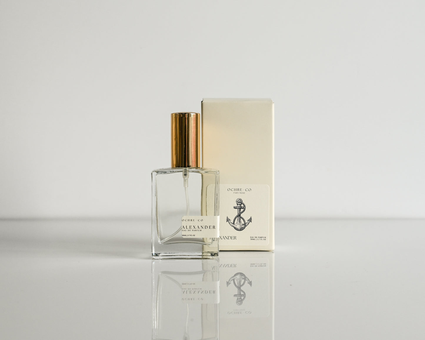 Perfume bottle and packaging on a reflective surface with a light background