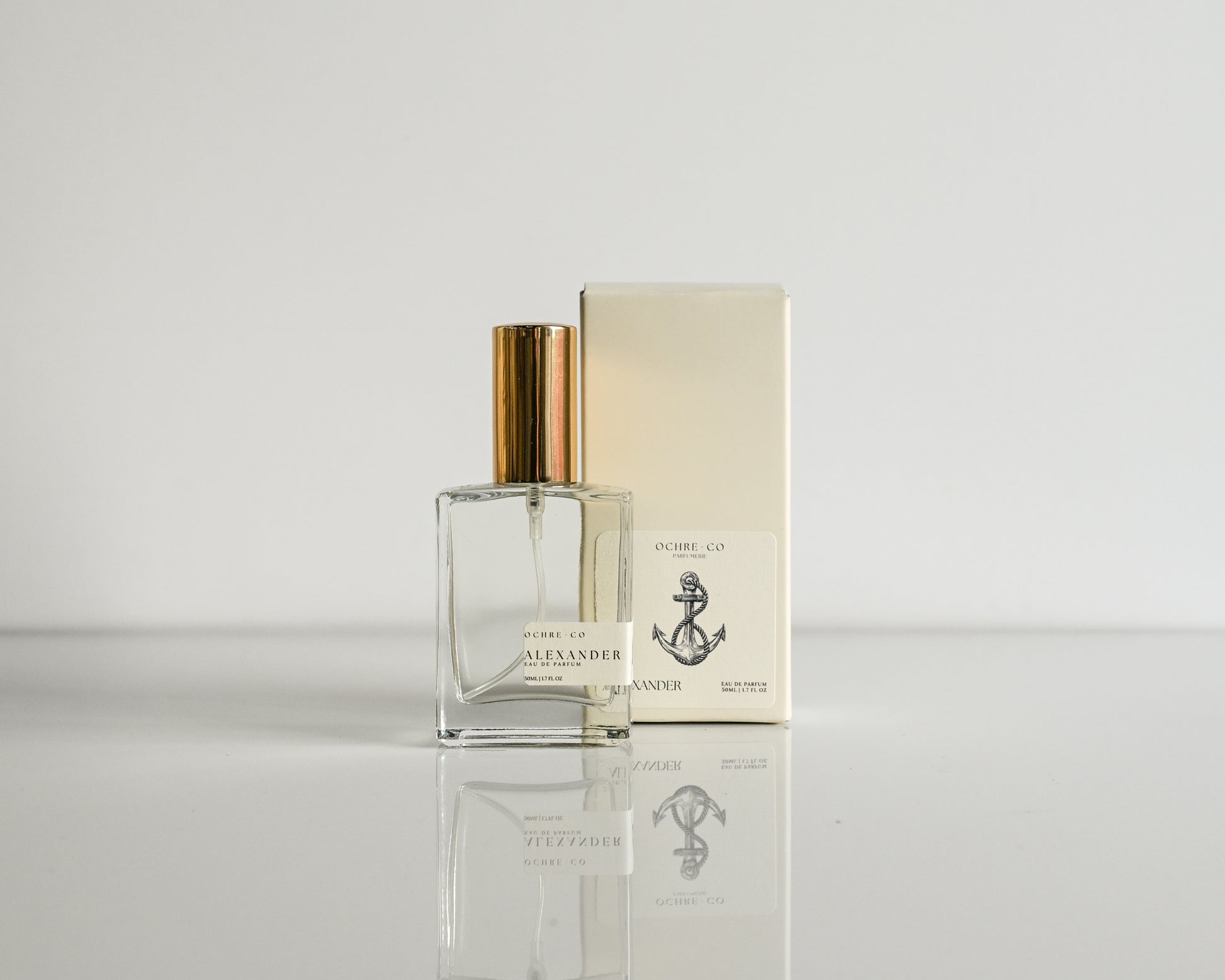 Perfume bottle and packaging on a reflective surface with a light background