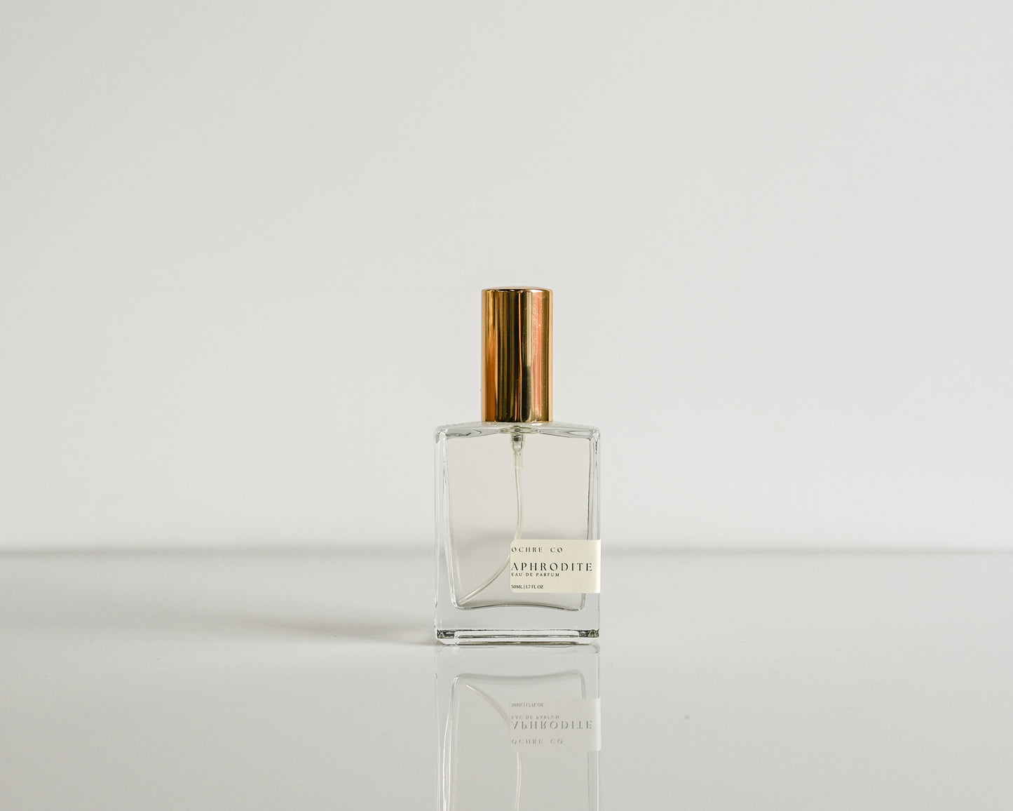 Clear perfume bottle with gold cap on a white background