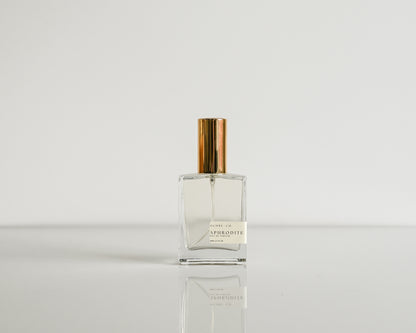 Clear perfume bottle with gold cap on a white background