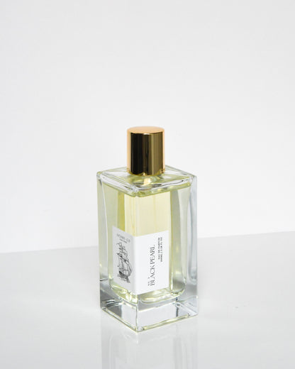 A clear glass bottle of Black Pearl eau de parfum with a gold-colored cap.