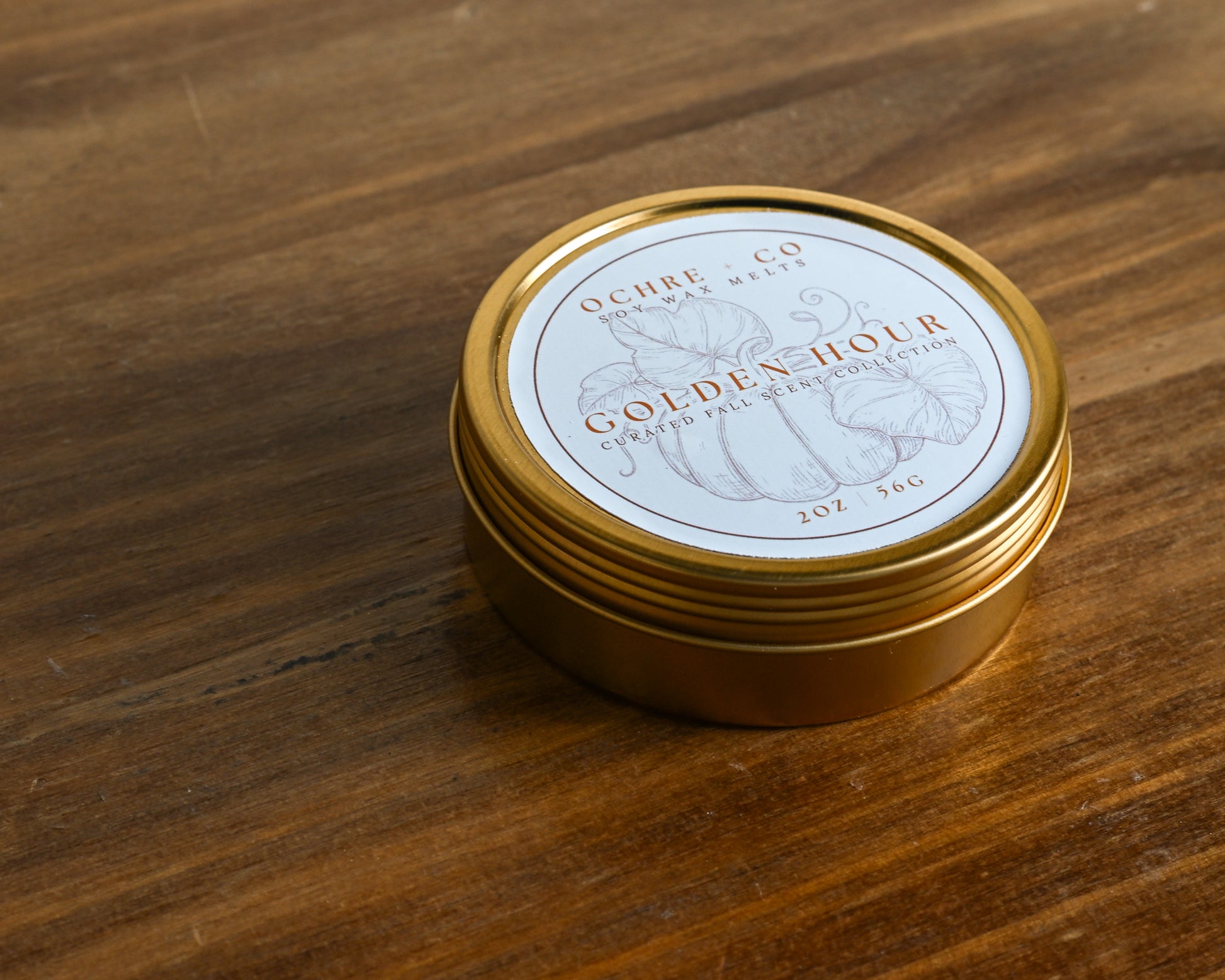 Golden Hour fall wax melt gold tin on a wood and white backdrop
