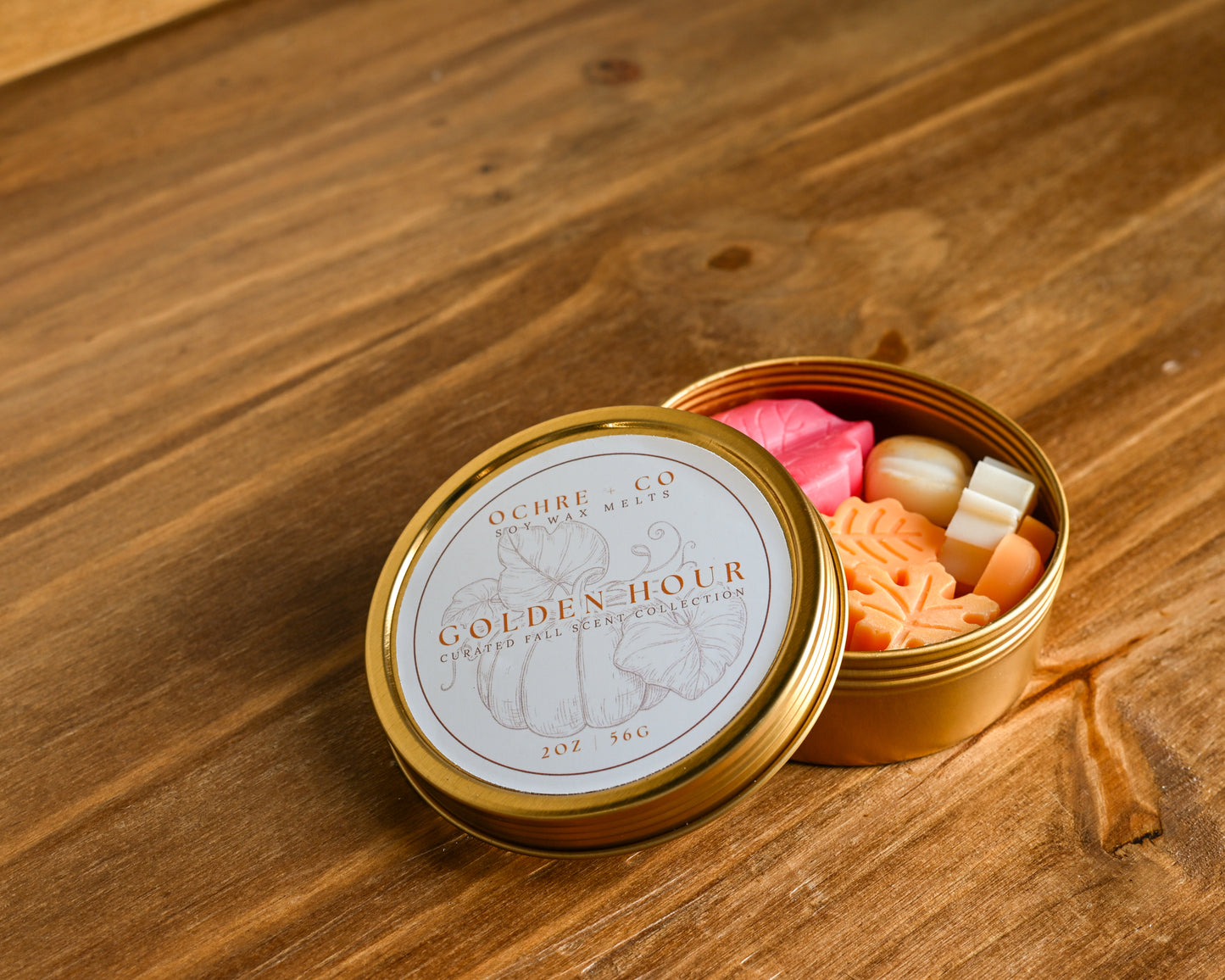 Golden Hour gold tin of varietal fall wax melt scents on a wood background