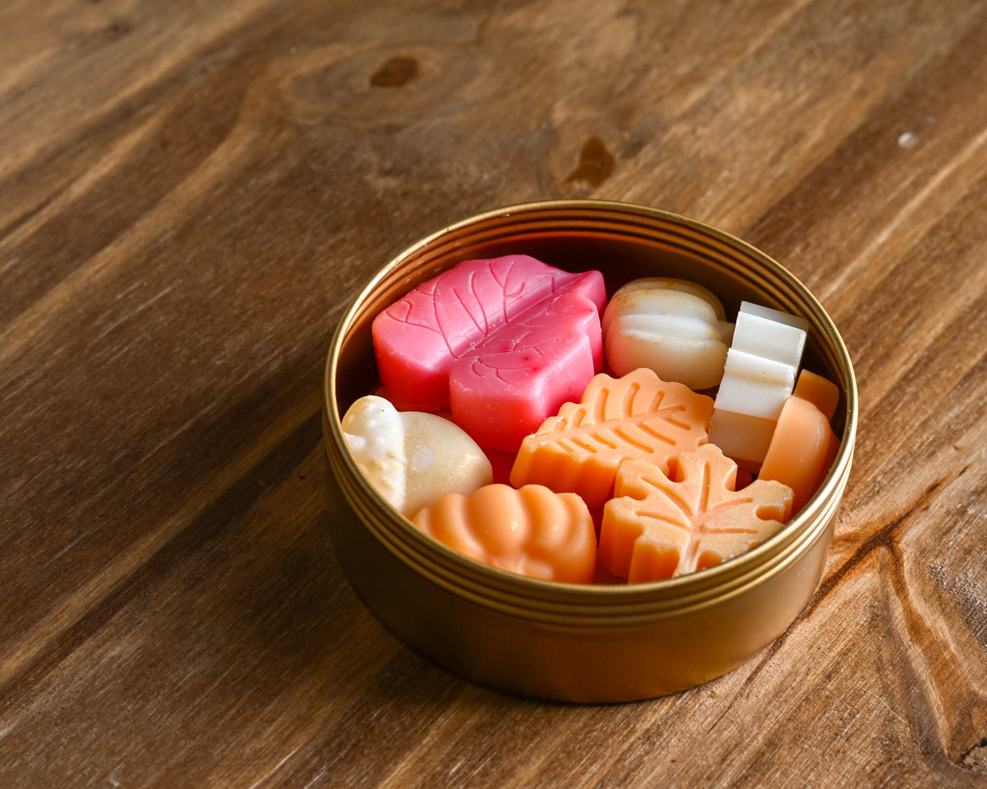 Golden Hour gold tin of varietal fall wax melt scents on a wood background