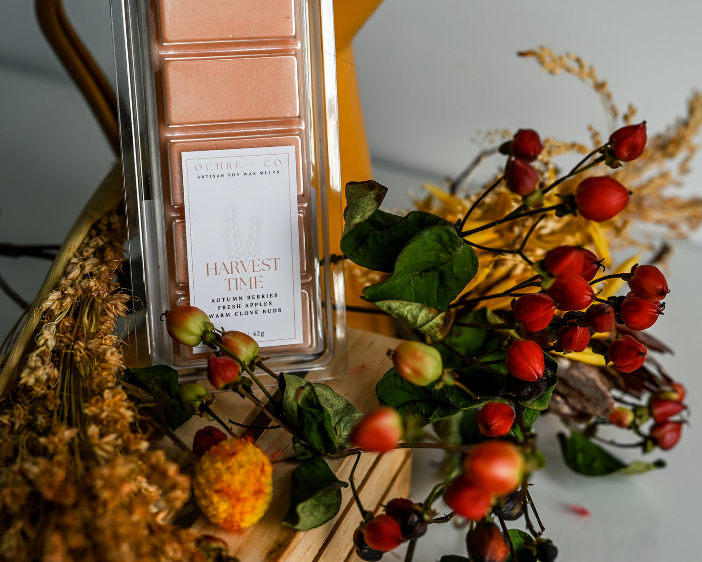 Decorative arrangement with a wax melt labeled 'Harvest Time' surrounded by autumn-themed elements.
