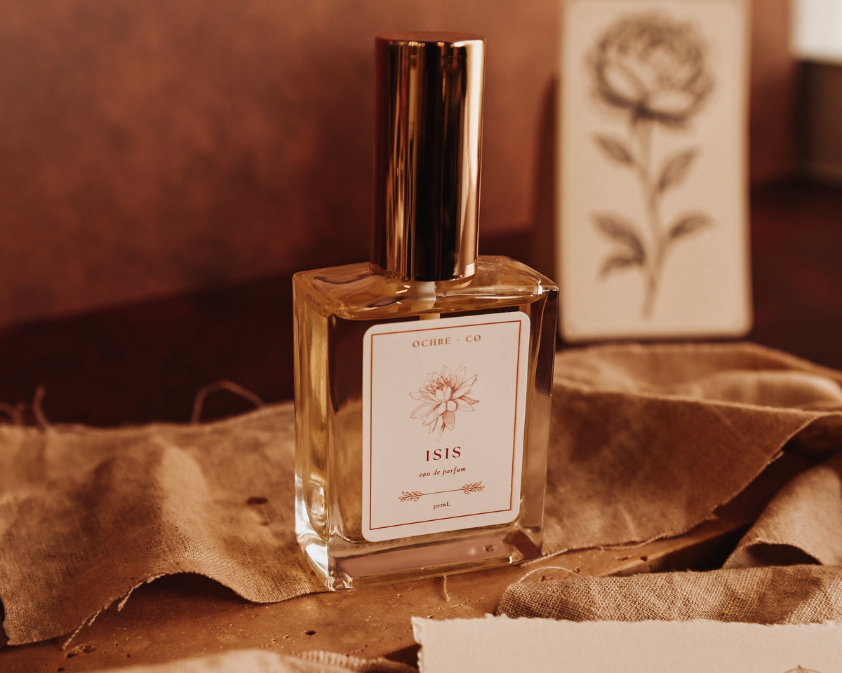 Perfume bottle labeled 'Isis' on a textured surface with a warm color tone.