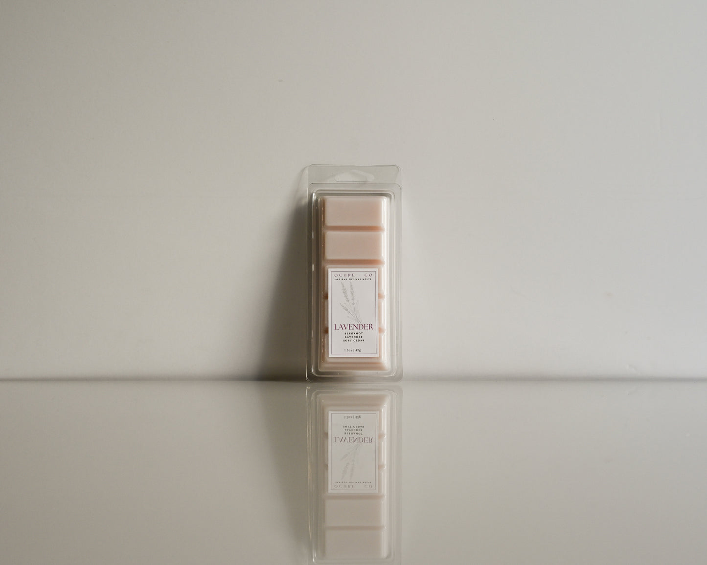 Packaged lavender wax melt on a reflective surface with a neutral background