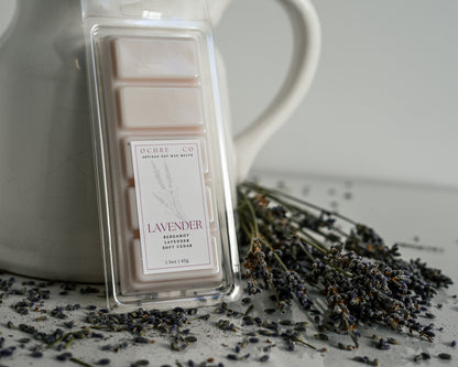 Ochre & Co lavender wax melt with a white pitcher and lavender flowers on a light background