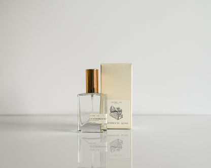 Perfume bottle with gold cap and packaging on a light gray background