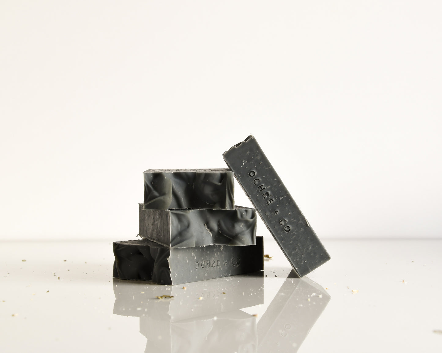 Black soap bars with 'OCHRE' branding on a reflective surface.