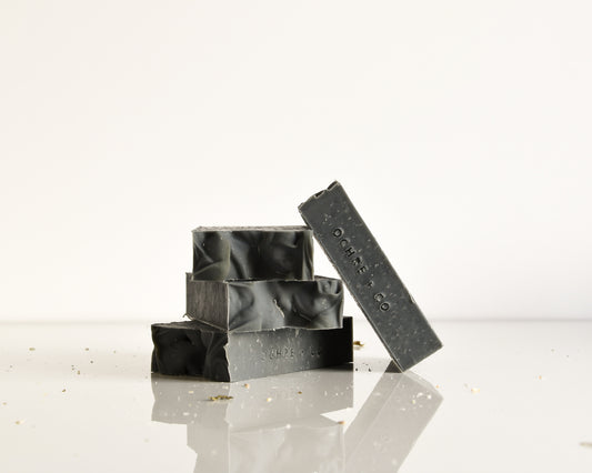 Black soap bars with 'OCHRE' branding on a reflective surface.