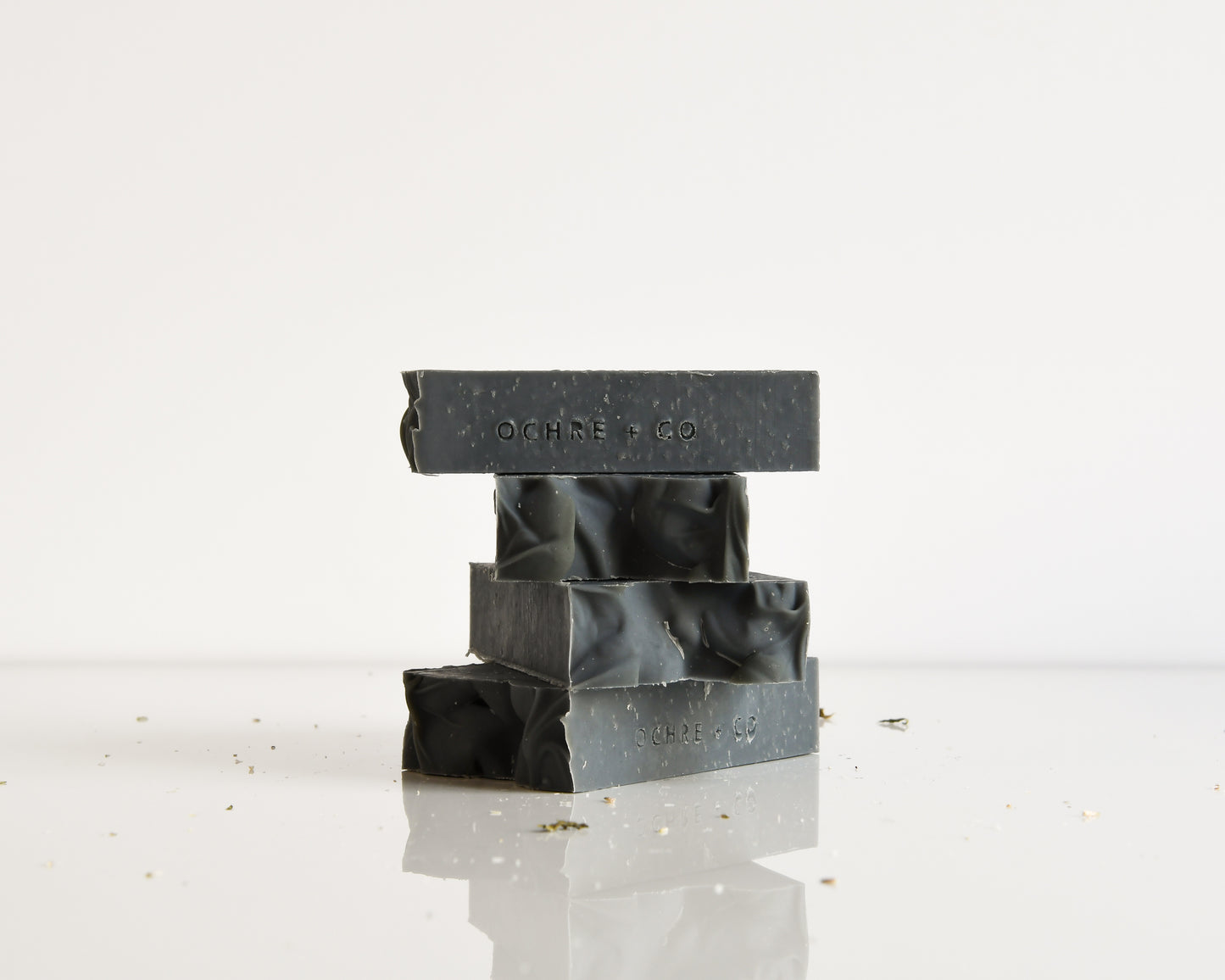 Stack of black soap bars with 'OCHRE + CO' branding on a white background