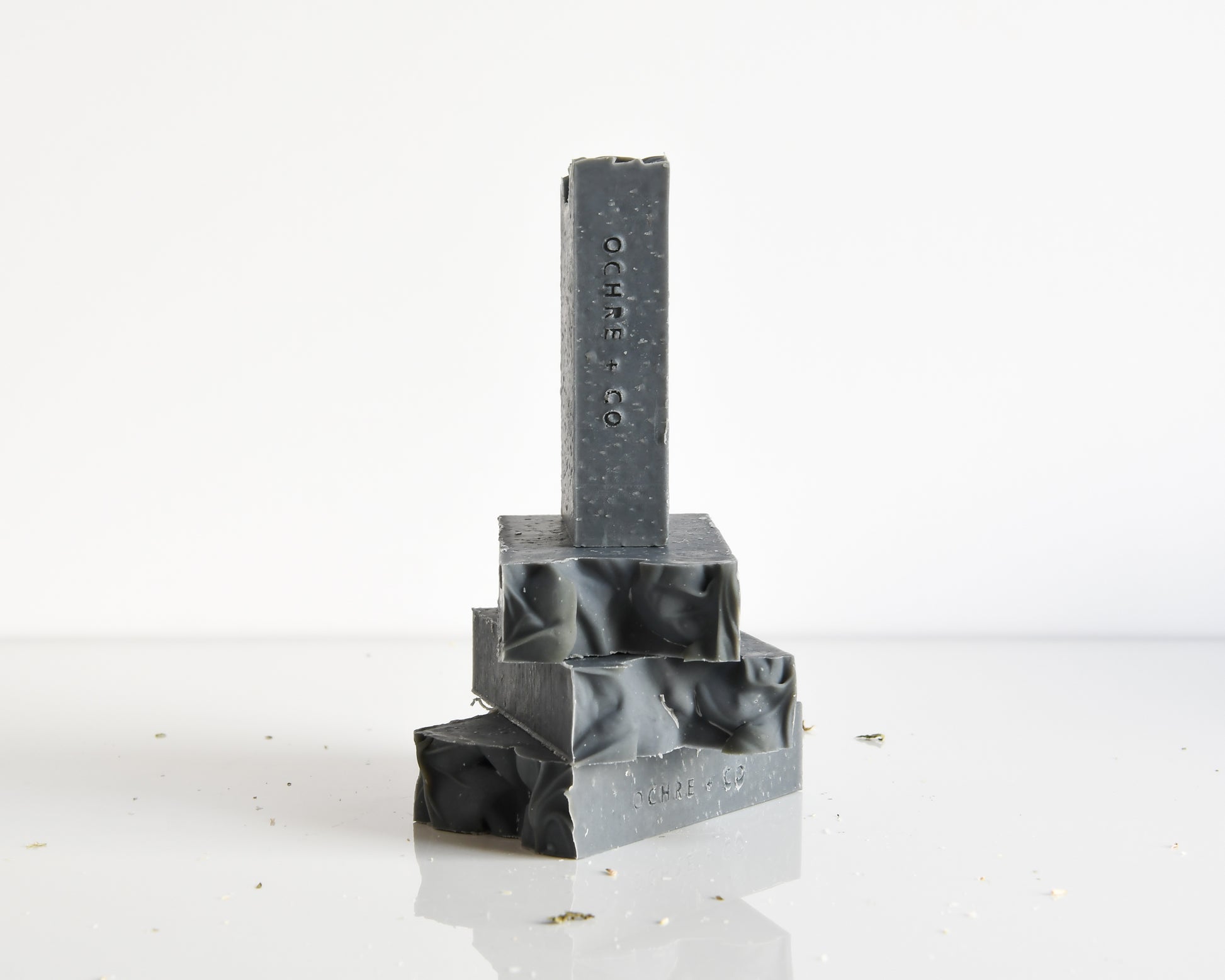 Four bars of stacked charcoal soap on a white background