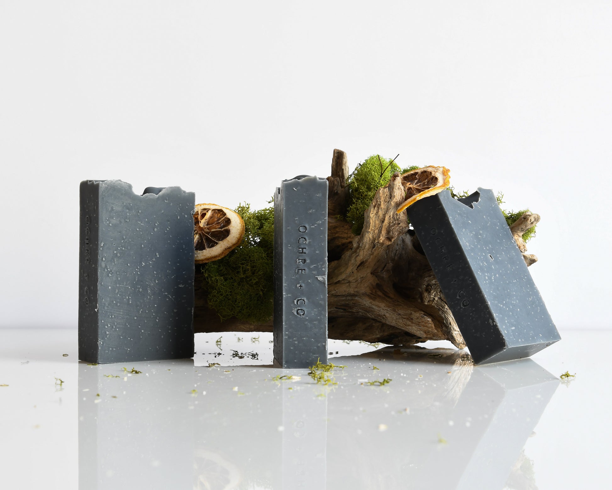 Three black soap bars with natural elements on a white background