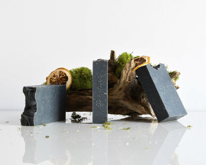 Three soap bars with natural elements on a reflective surface