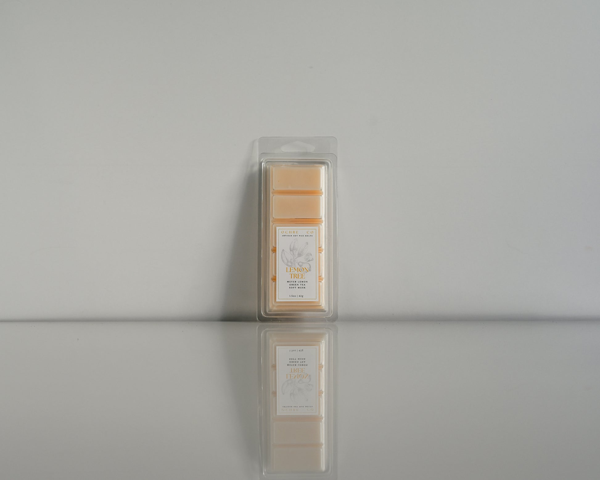 Packaged Lemon Tree wax melt on a reflective surface with a neutral background