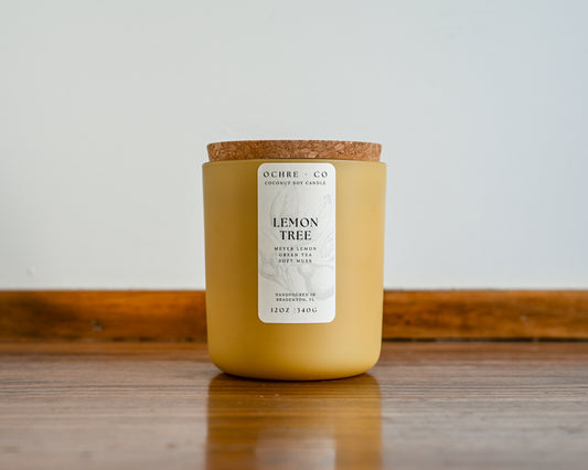 Yellow lemon grove scented candle with a cork lid on a wooden surface