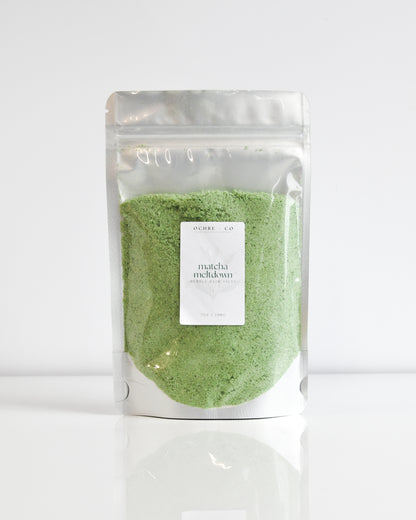 Packaged matcha green bubbling bath salt powder on a white background