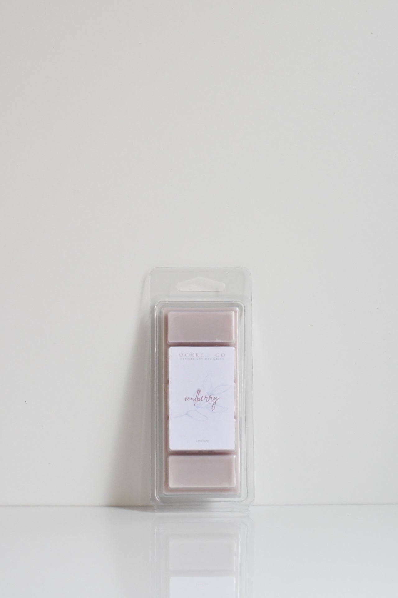 A clear plastic snap bar packaging containing pink-colored wax melts with a white label on top.