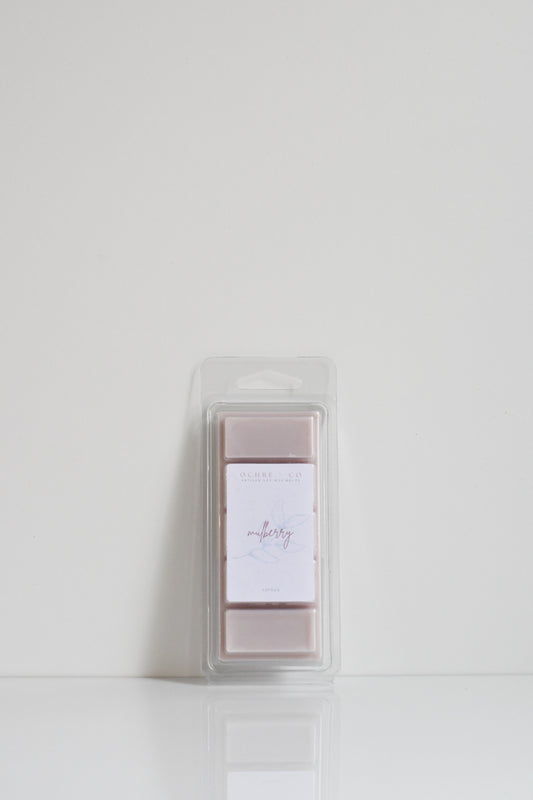 A clear plastic snap bar packaging containing pink-colored wax melts with a white label on top.
