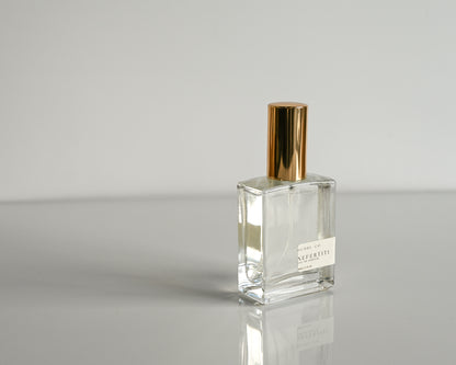 Clear perfume bottle with gold cap on a gray background