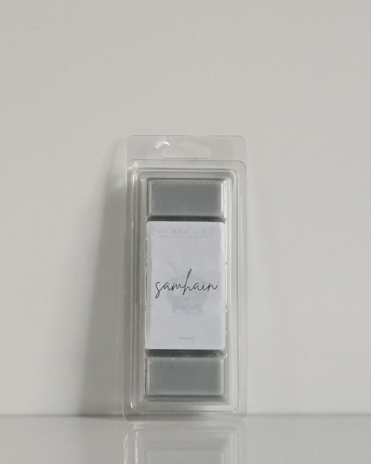 A dark grey wax melt in its packaging, leaning against a white background, label reads "Samhain"