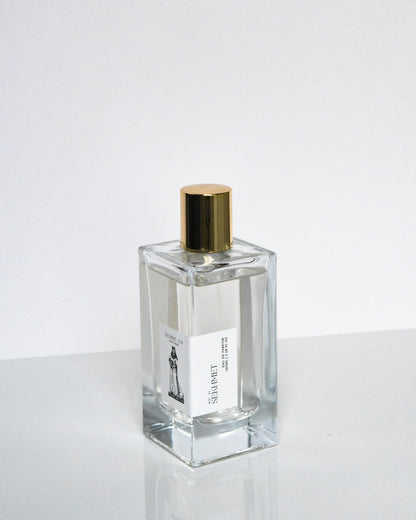 A clear glass bottle of Sekhmet Eau de Parfum with a gold-colored cap, displayed against a white background.