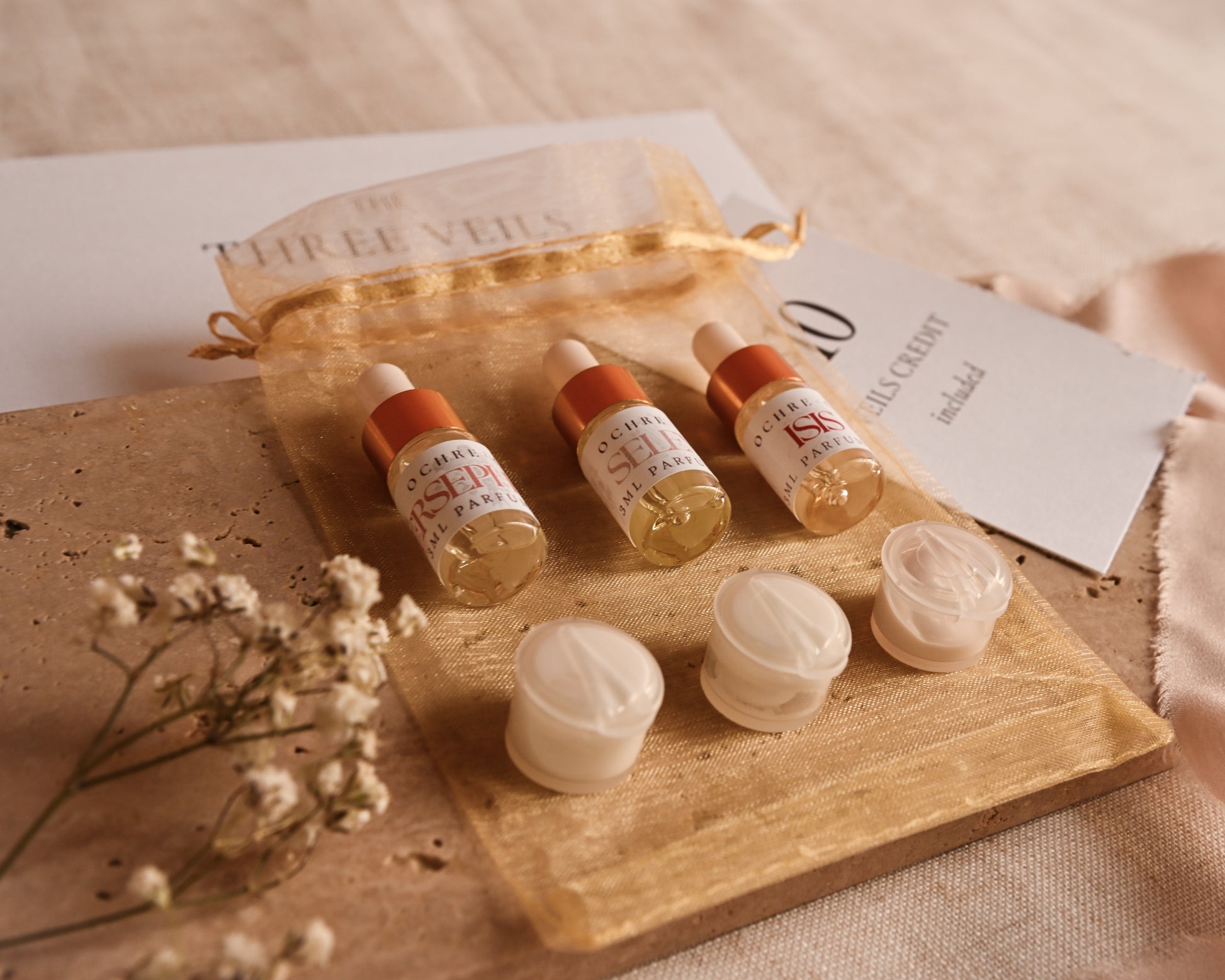 Cosmetic products including bottles and jars on a travertine tile with a beige background.