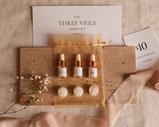 Three Veils sample kit with three dropper bottles and three round containers on a beige fabric background.