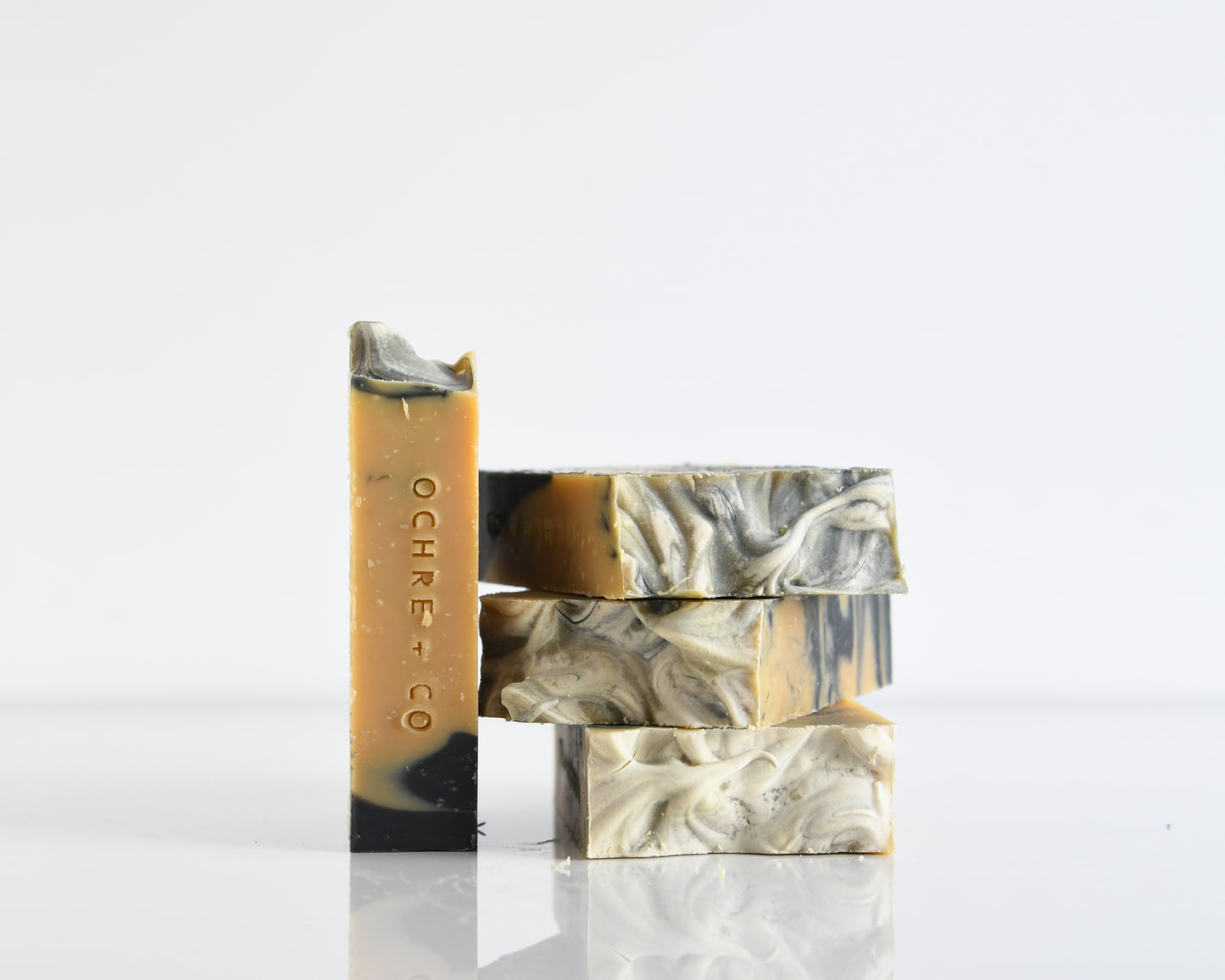 Three bars of soap with marbled patterns stacked on a white background with one bar of soap standing on the side