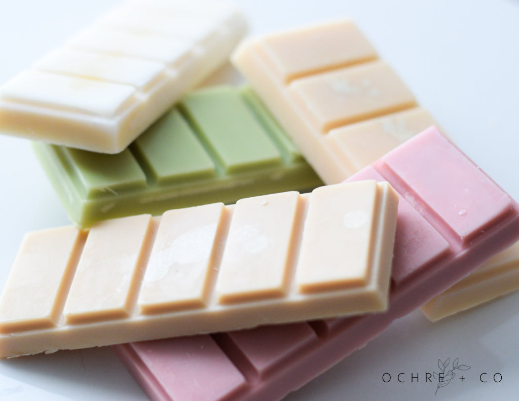 Stack of different color wax melt snap bars on a white background